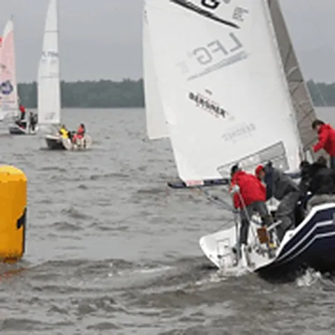 Besättningar på små segelbåtar i flytvästar vid starten av en regatta