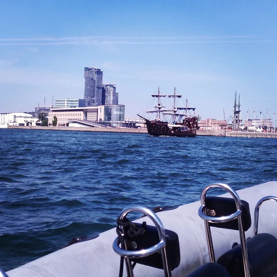 Utsikt från en motorbåt mot ett fartyg i piratstil och Gdynias skyskrapor