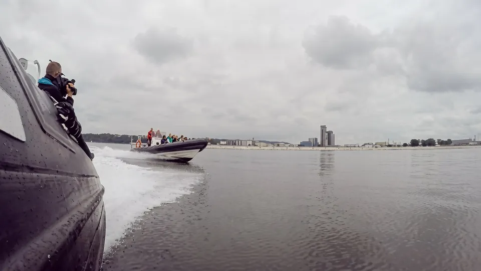 Fotograf vid relingen på en ribbåt filmar en annan båt som kör vid Gdynia