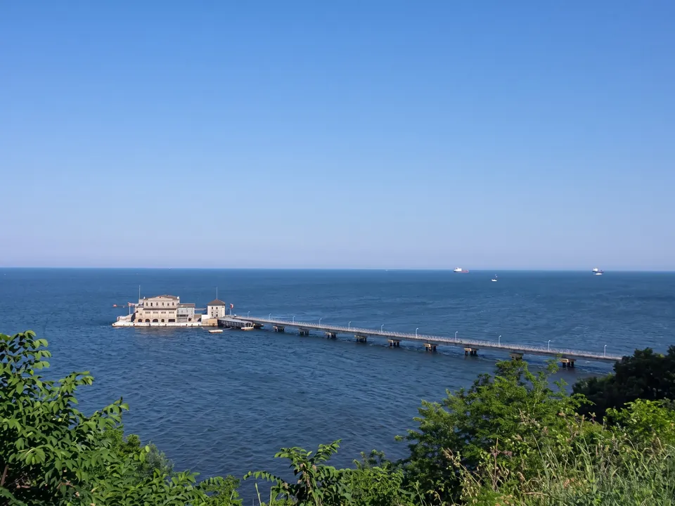 Pier extending into the sea seen from the green shore