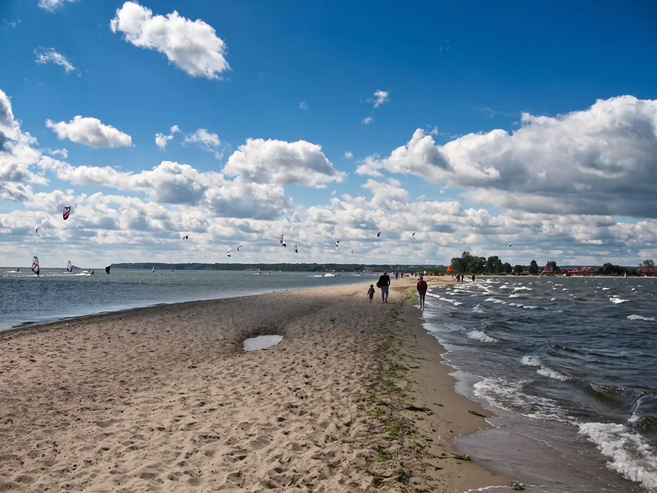 Sandy beach on the Rewa Spit, walkers and kitesurfers on the bay