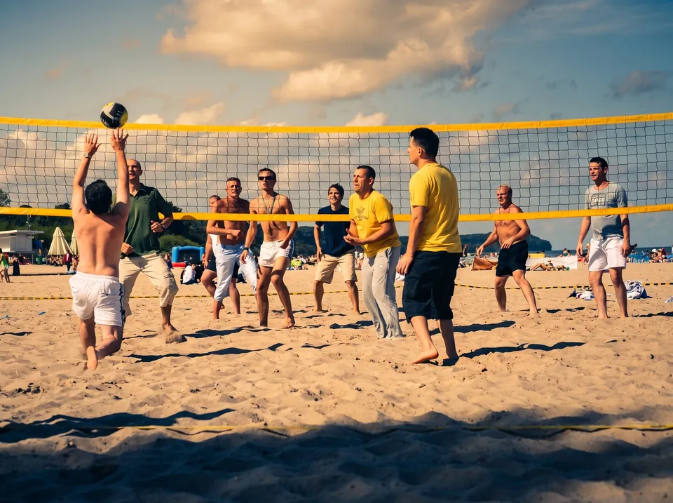 Grupa firmowa gra w siatkówkę plażową na szerokiej plaży nad Bałtykiem